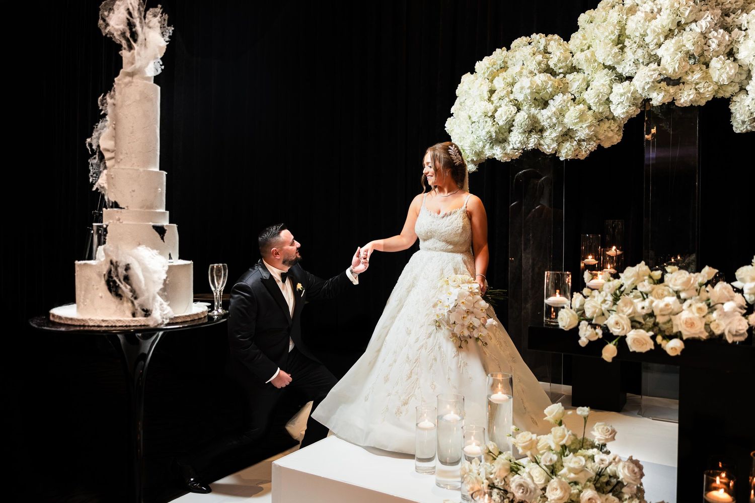 Elegant wedding ceremony setup with white floral arrangements against dark backdrop.
