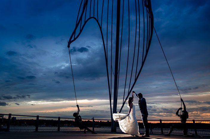 Silhouettes against dramatic blue sunset sky create romantic wedding scene.
