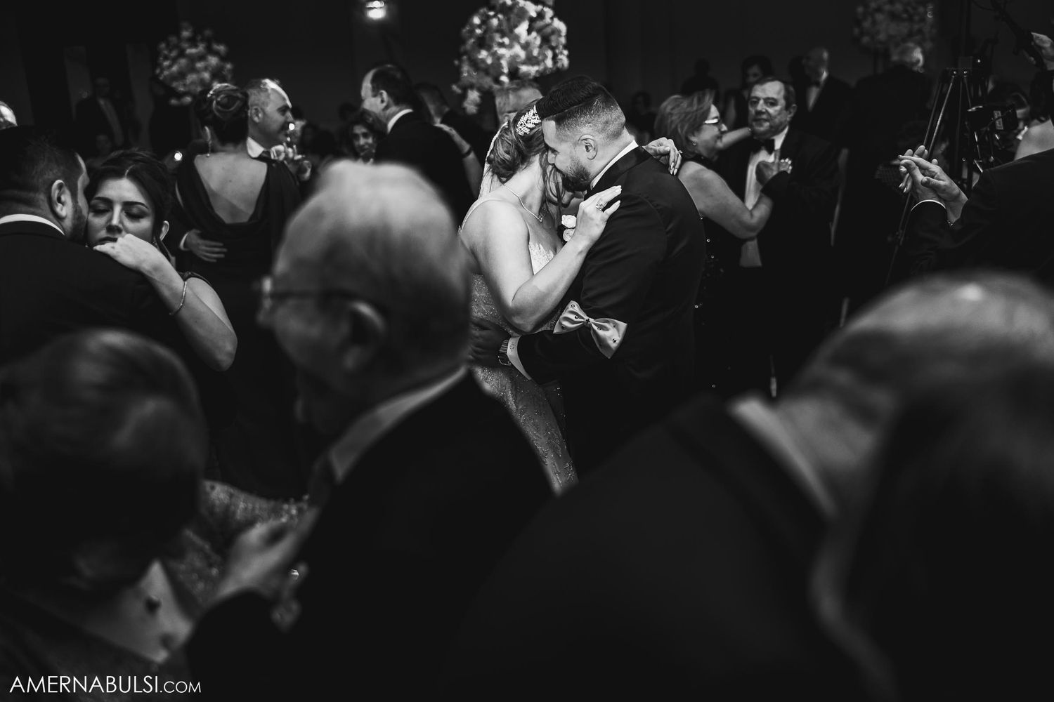 Black and white photo of wedding guests surrounding a dancing couple at a reception.