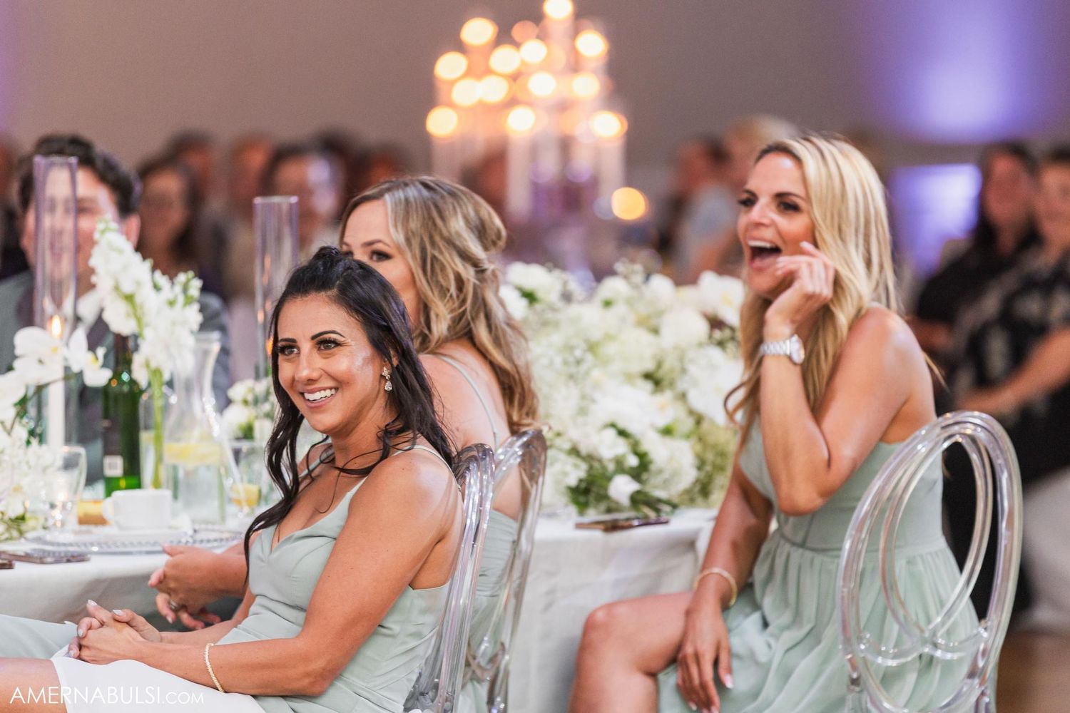 Wedding guests seated at an elegantly decorated table with white floral centerpieces.