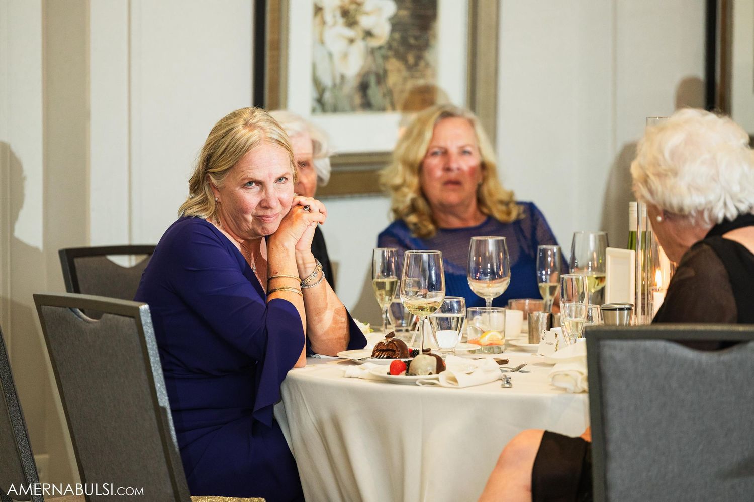 Guests enjoying formal dinner at elegantly set tables during wedding reception.