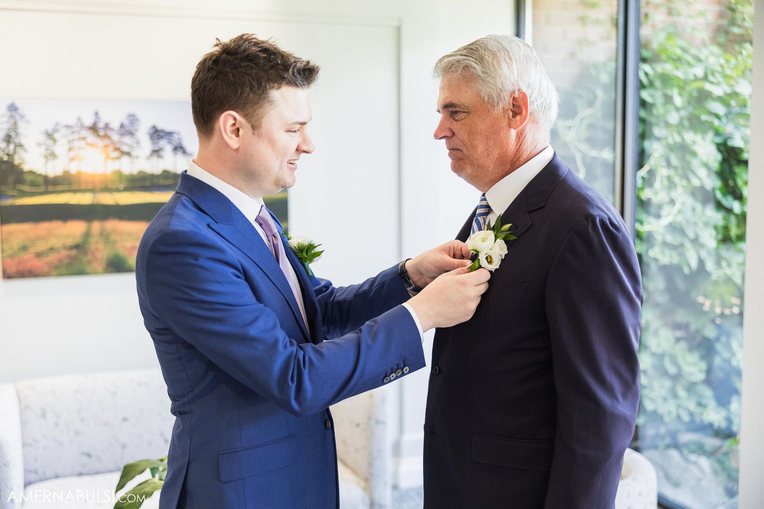 Boutonniere pinning moment between two people in formal wedding attire.
