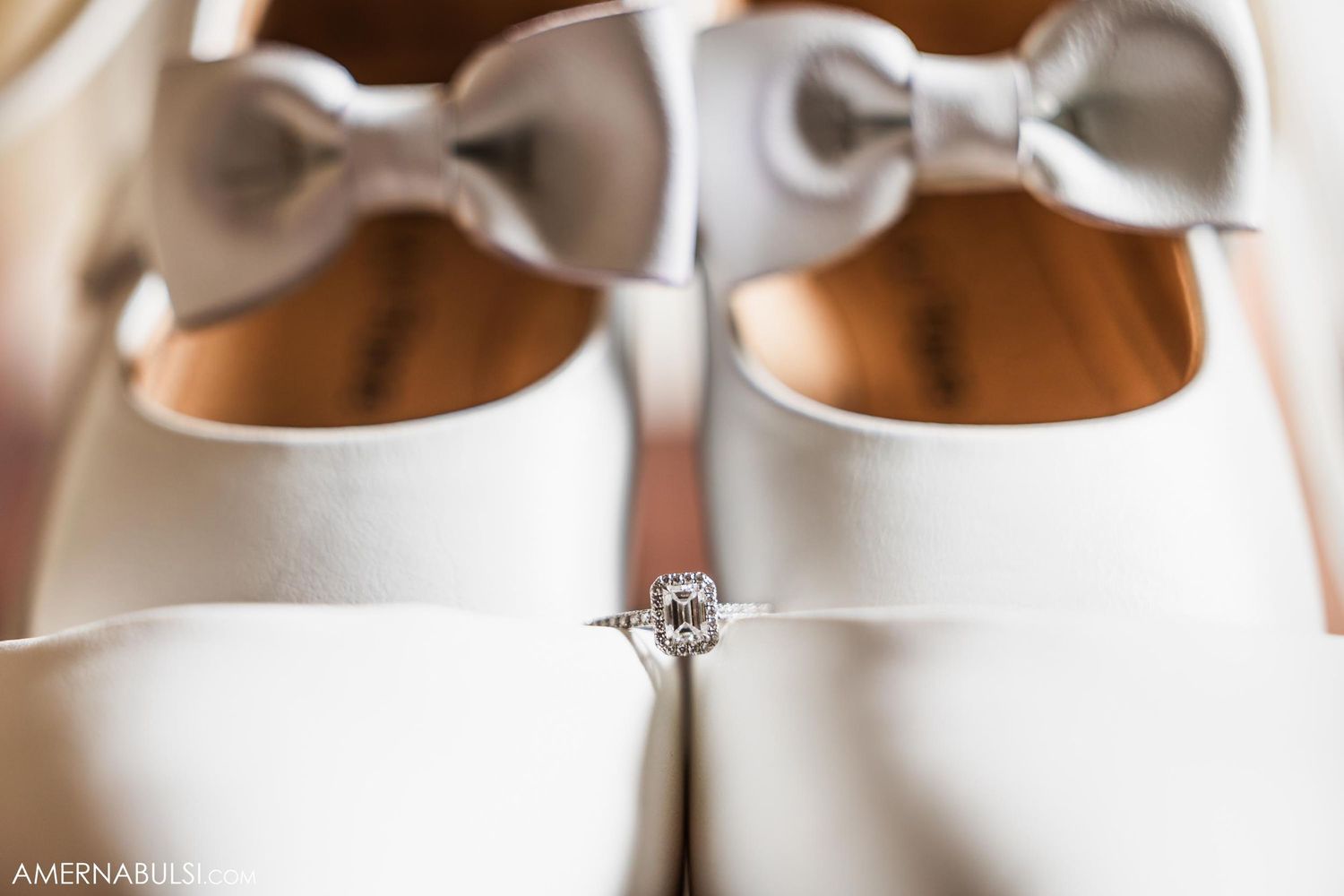 White bridal shoes with gray bows displayed with an engagement ring.