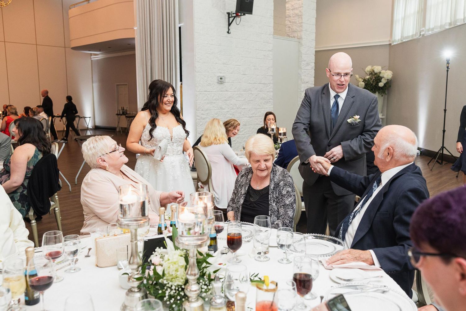 Wedding reception dinner with guests seated at round tables with elegant centerpieces.