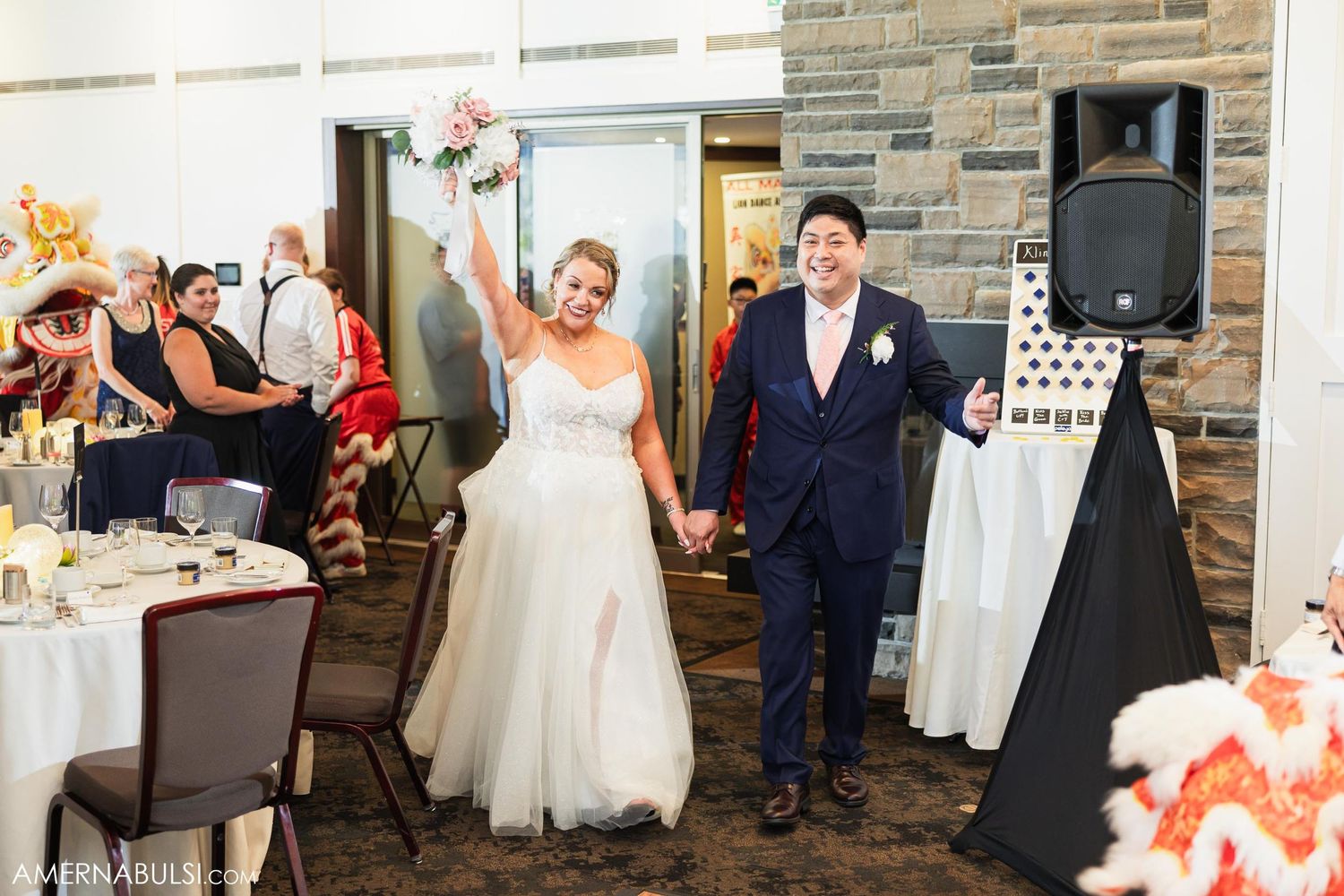 Bride and groom celebrate joyfully on dance floor at wedding reception.