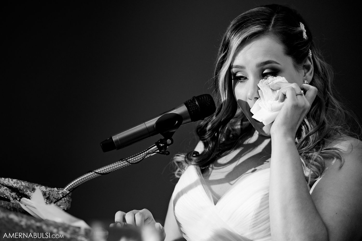 Musicians perform at a wedding reception with instruments and microphones in dramatic black and white lighting.