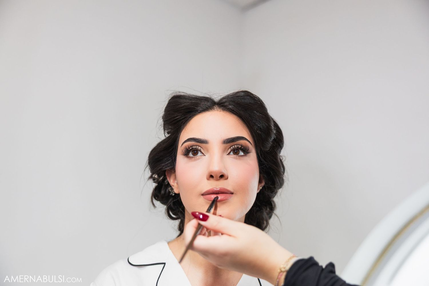 A makeup artist applies finishing touches during a bridal beauty preparation session.
