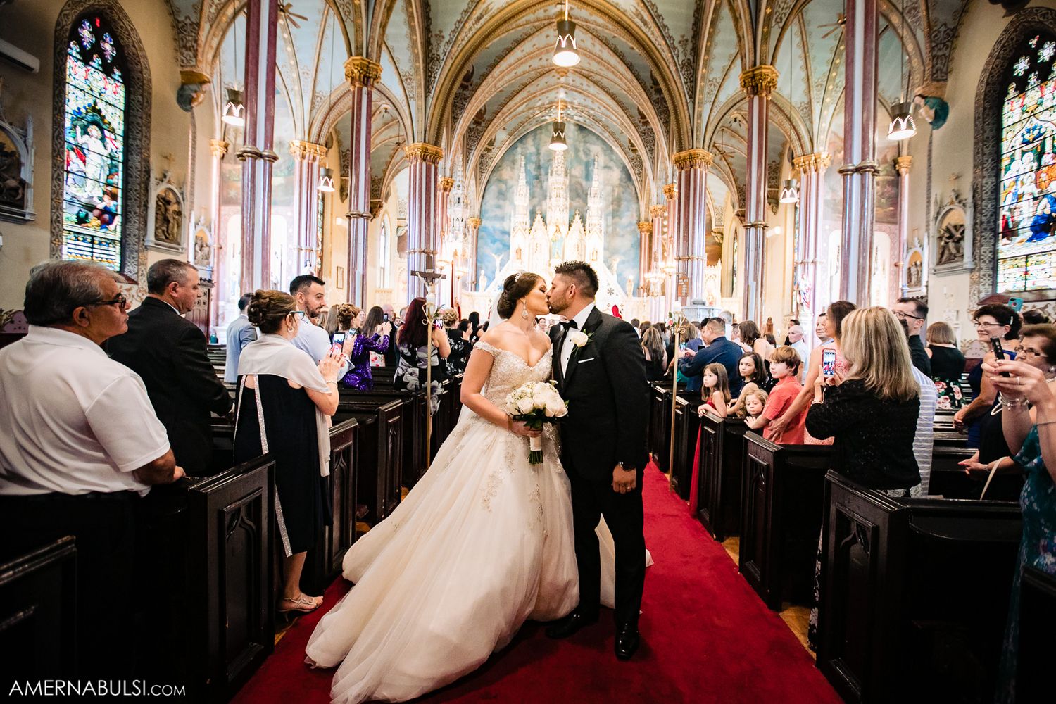 Wedding ceremony taking place in a grand cathedral with ornate architecture and stained glass windows.