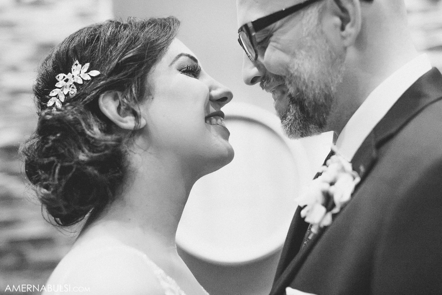 A tender black and white wedding moment showing a romantic close-up of a couple with delicate floral hair accessories.
