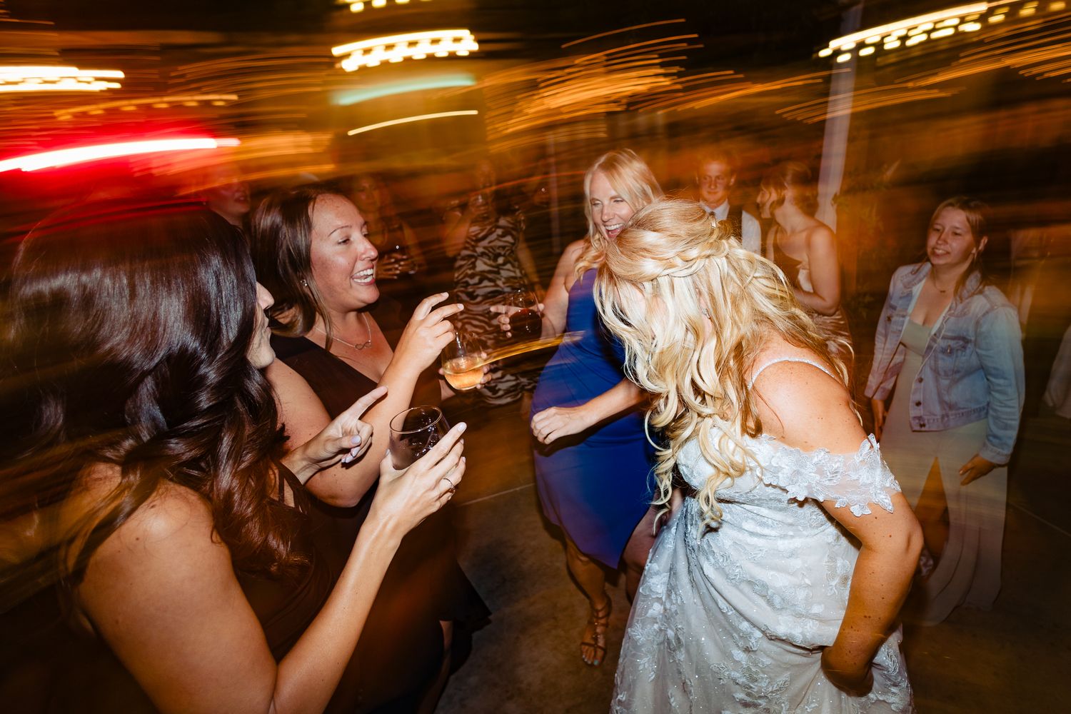 People dancing and socializing at a lively evening party with colorful lighting effects.