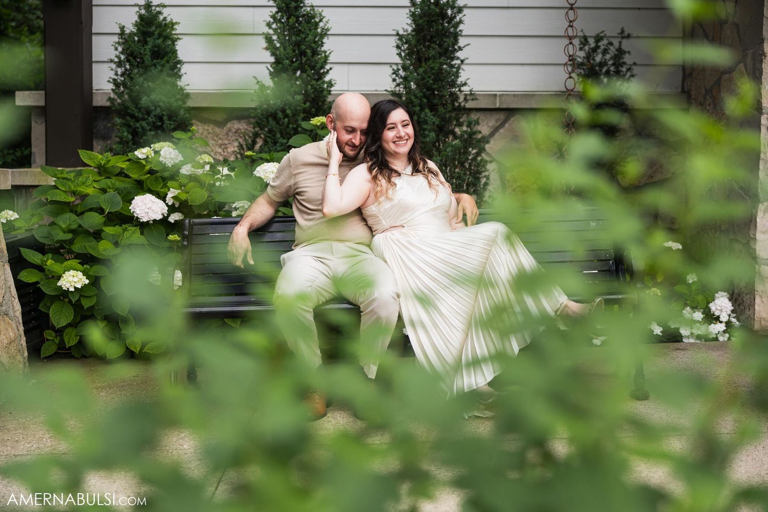 Intimate garden moment captured through foliage with white flowers in foreground.