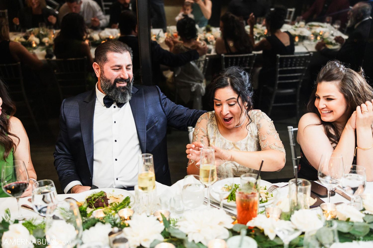 Wedding guests sharing laughter during reception dinner at decorated table.
