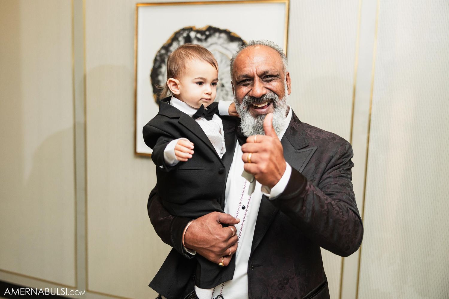 Formal portrait of two people in black tie attire sharing a joyful moment.