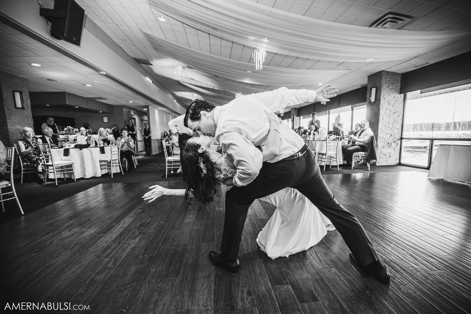 Dramatic dip during a dance performance on a wooden floor in an elegant reception hall.