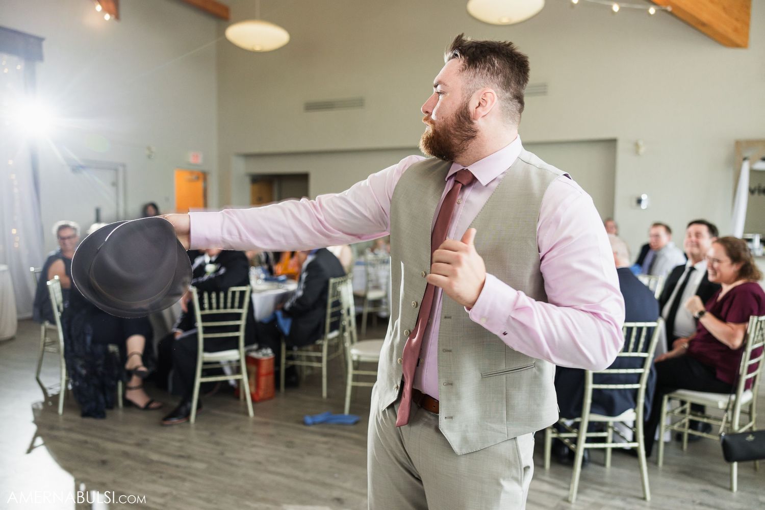Wedding reception venue with modern decor featuring wooden beams and hanging light fixtures.