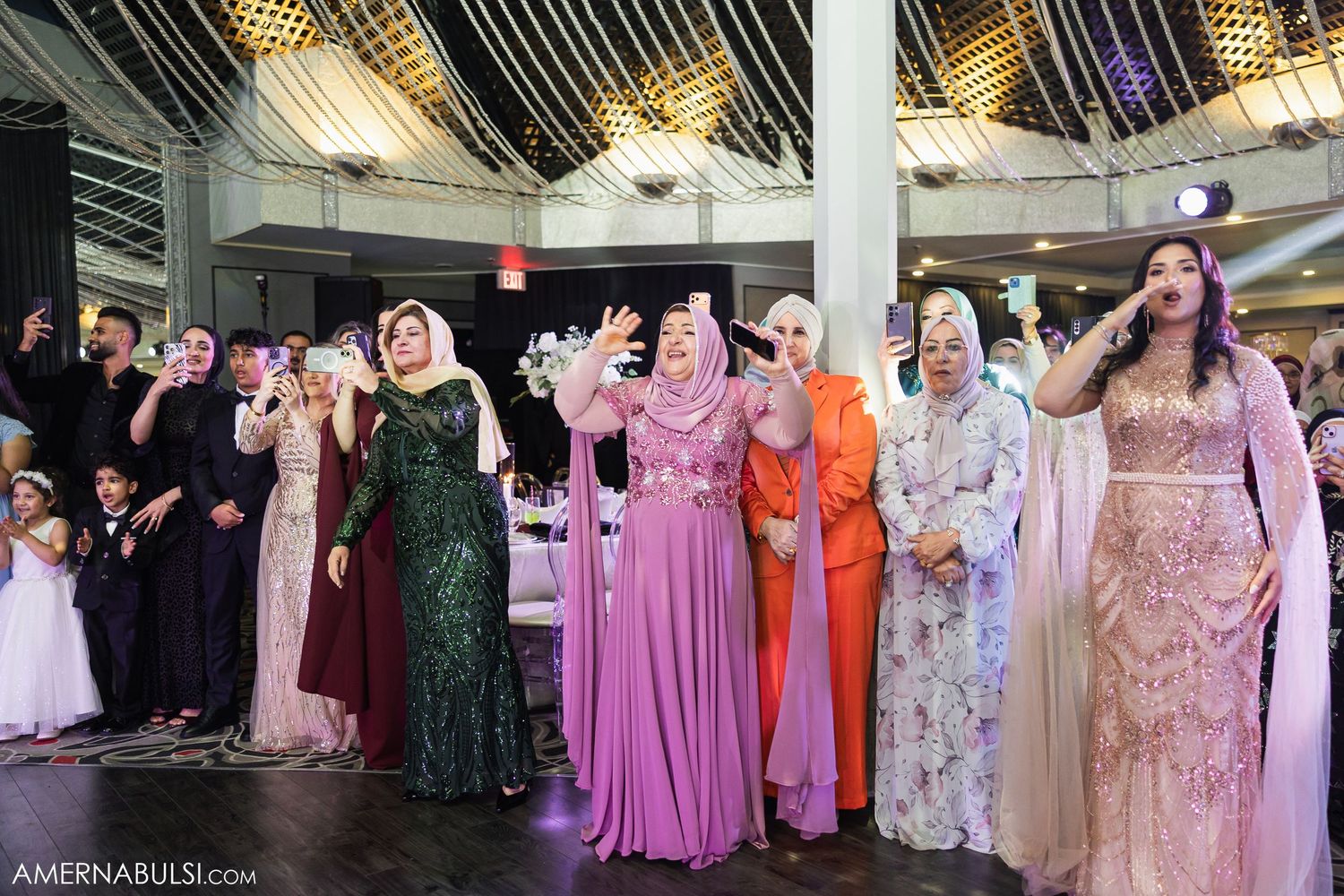 Elegant wedding reception hall decorated with string lights and filled with guests in formal attire.