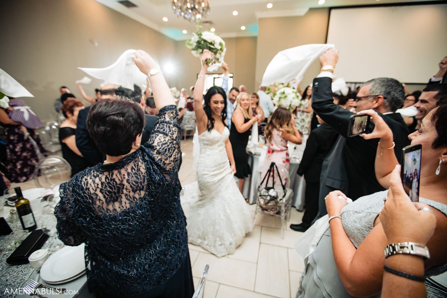 Wedding party and guests dancing energetically at reception celebration.