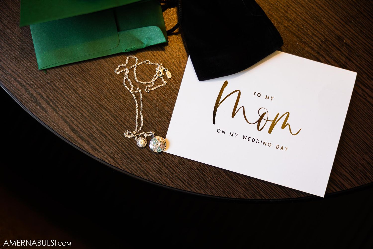 Wedding details including a handwritten note addressed to mom and earrings on a wooden surface.