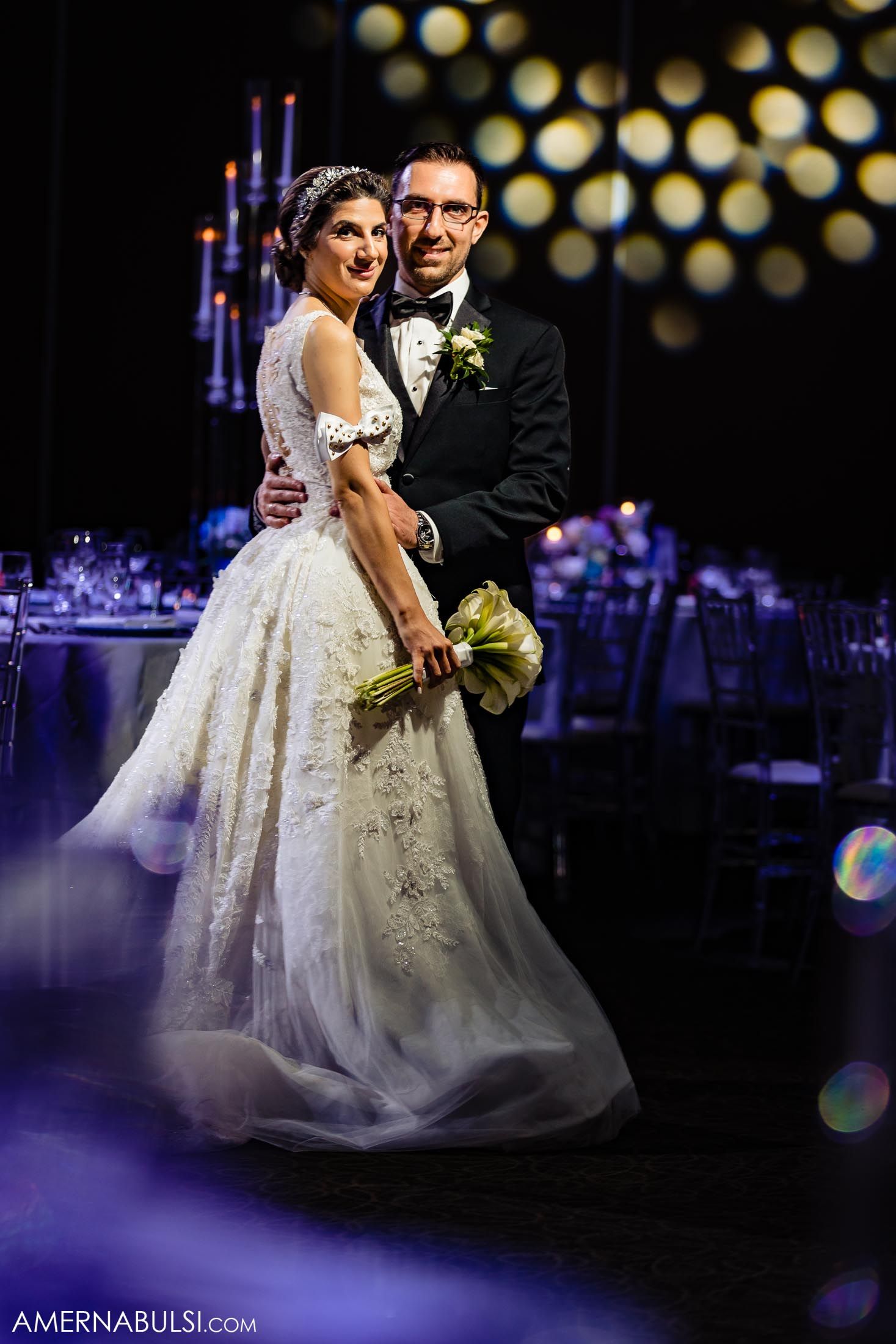 Elegant wedding reception portrait with bokeh lights and decorative background.
