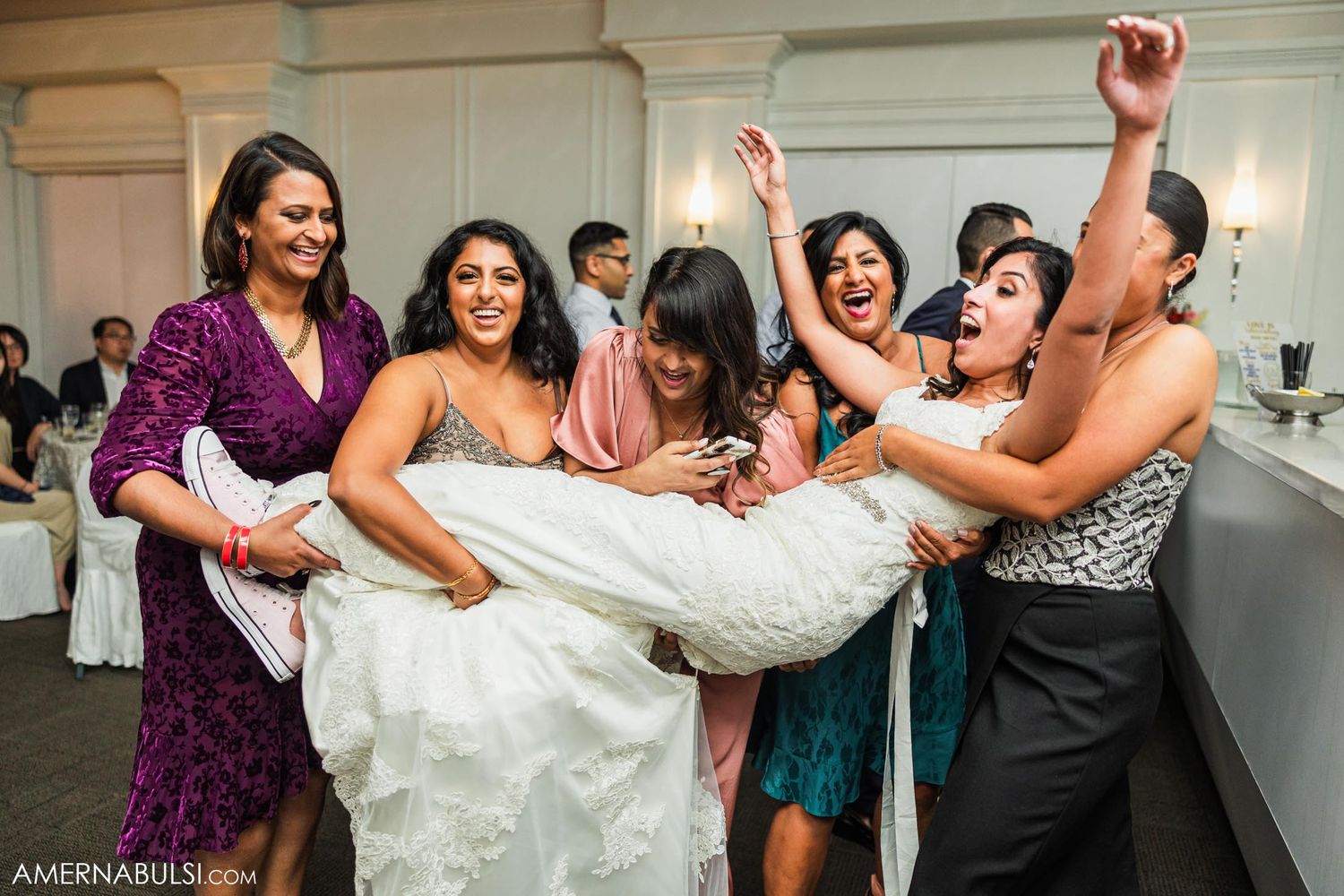 Wedding party having fun lifting the bride during reception celebrations.