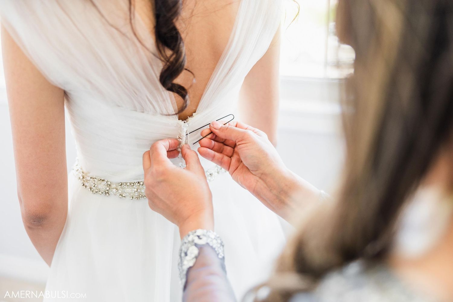 Close-up of wedding dress being buttoned up during bridal preparation.