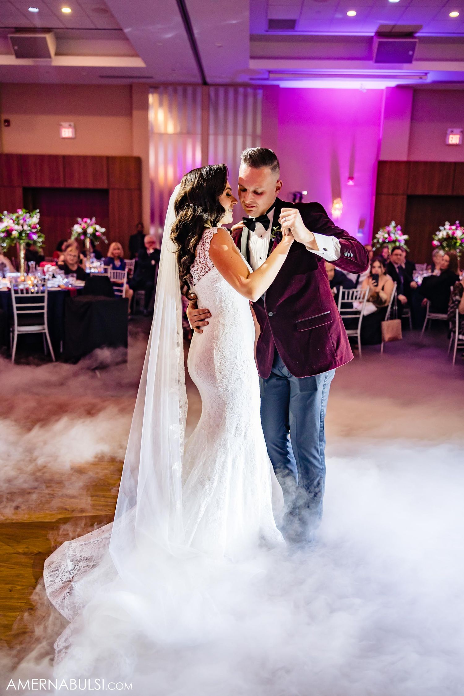 Romantic first dance on a misty dance floor with purple lighting and elegant reception decor.