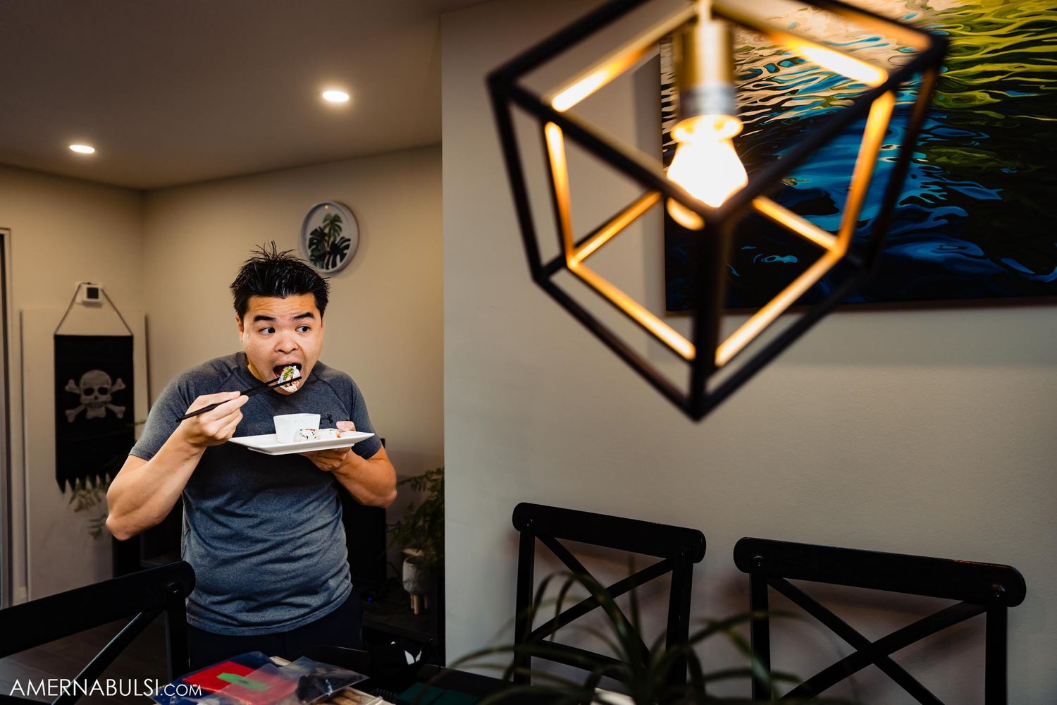 Person in casual attire enjoying coffee at a modern dining table with geometric lighting fixture.