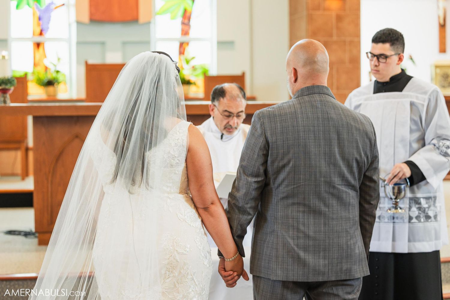 A couple holds hands while standing before an officiant during their wedding ceremony.
