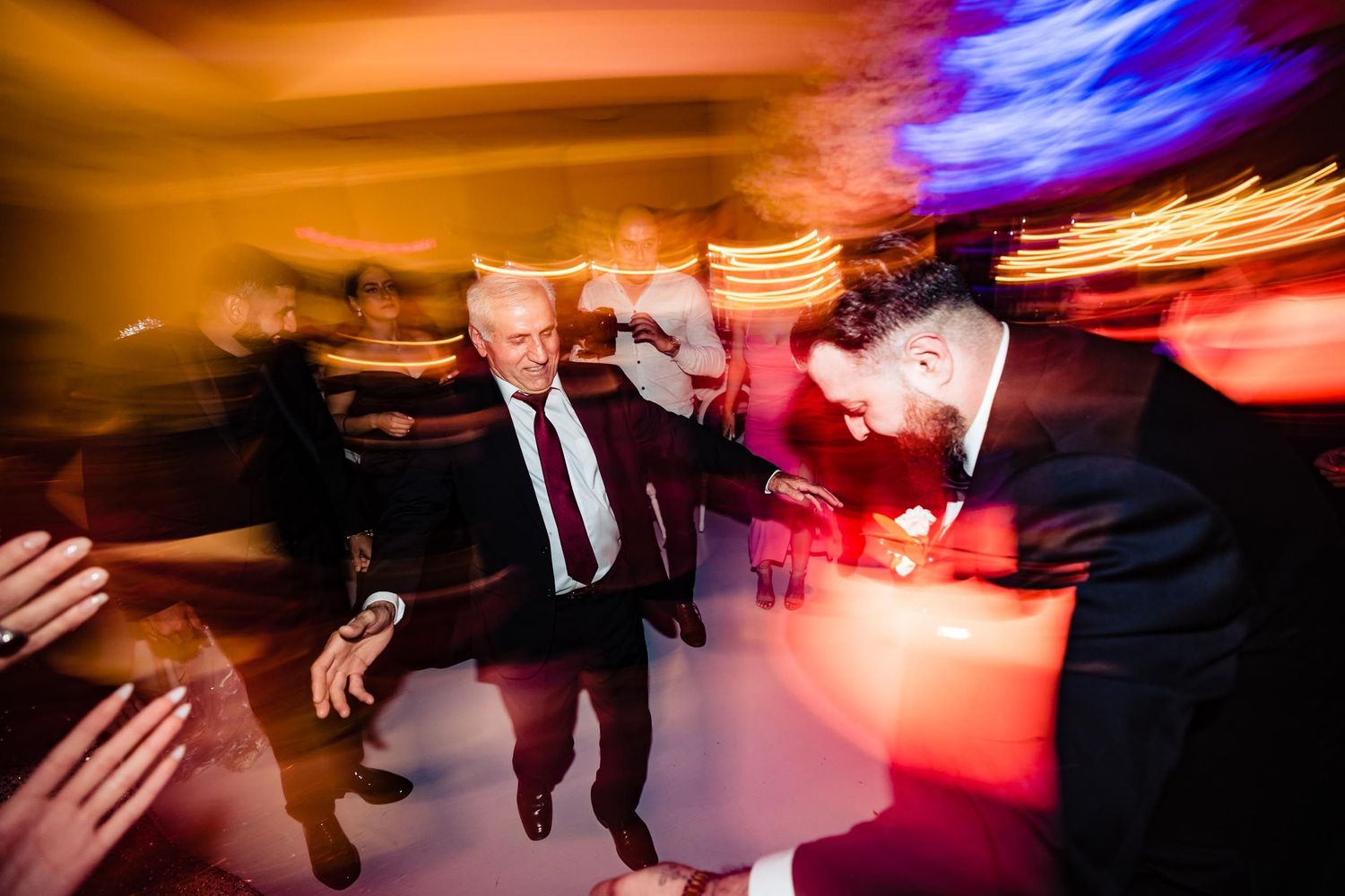 Motion-blurred dance floor scene with colorful party lights and dancing silhouettes.