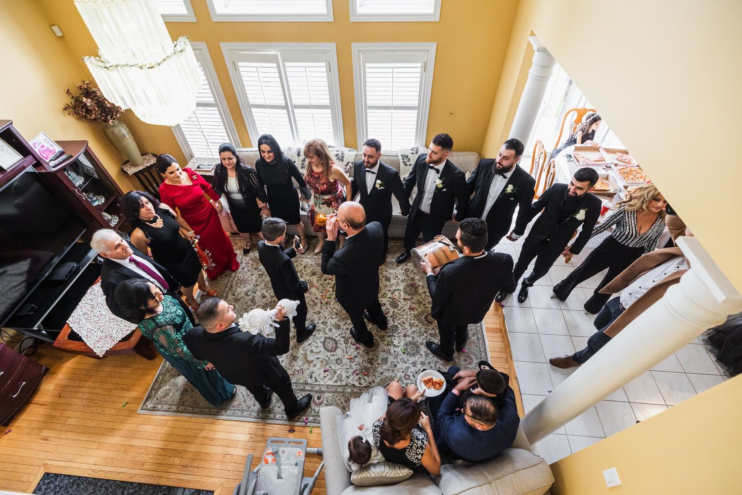 Overhead view of wedding guests gathered in a circle in a bright room with skylights.