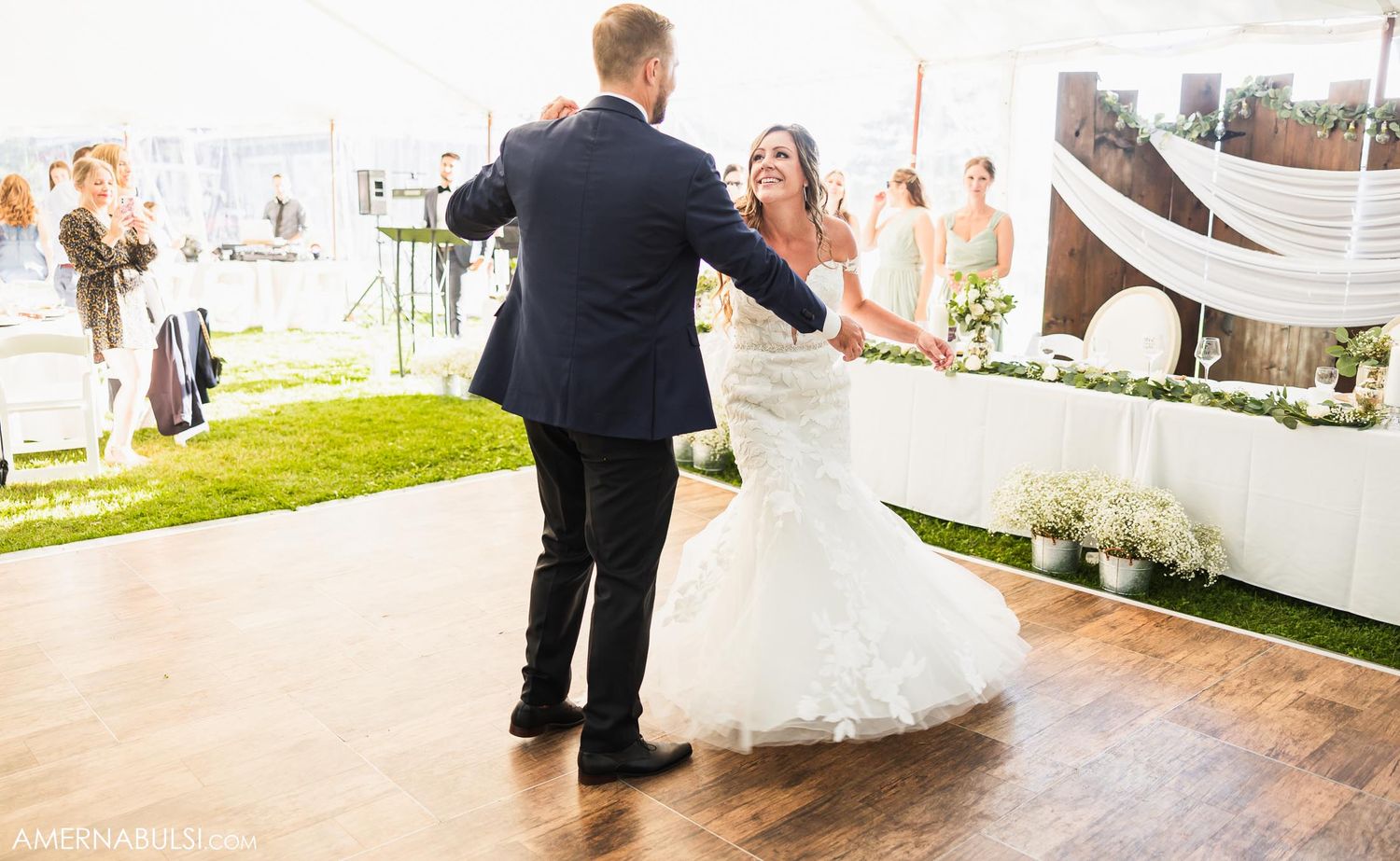 Couple dancing on wooden floor during outdoor wedding celebration.