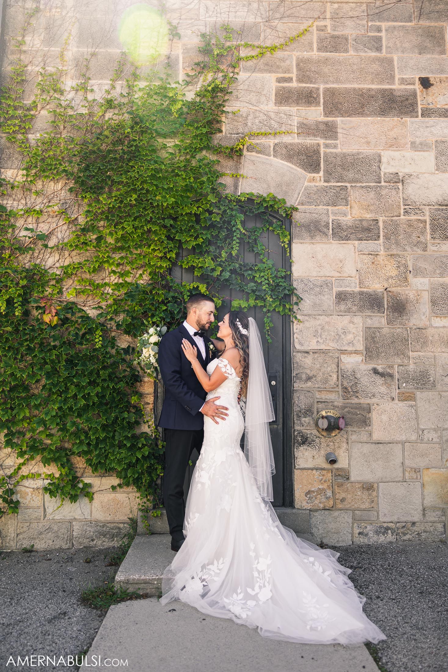 Romantic wedding portrait against stone wall with climbing ivy.