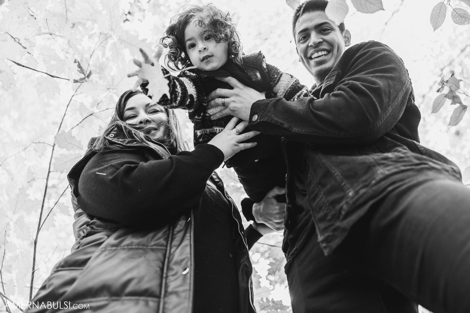 Black and white candid group photo taken from below against bright sky.