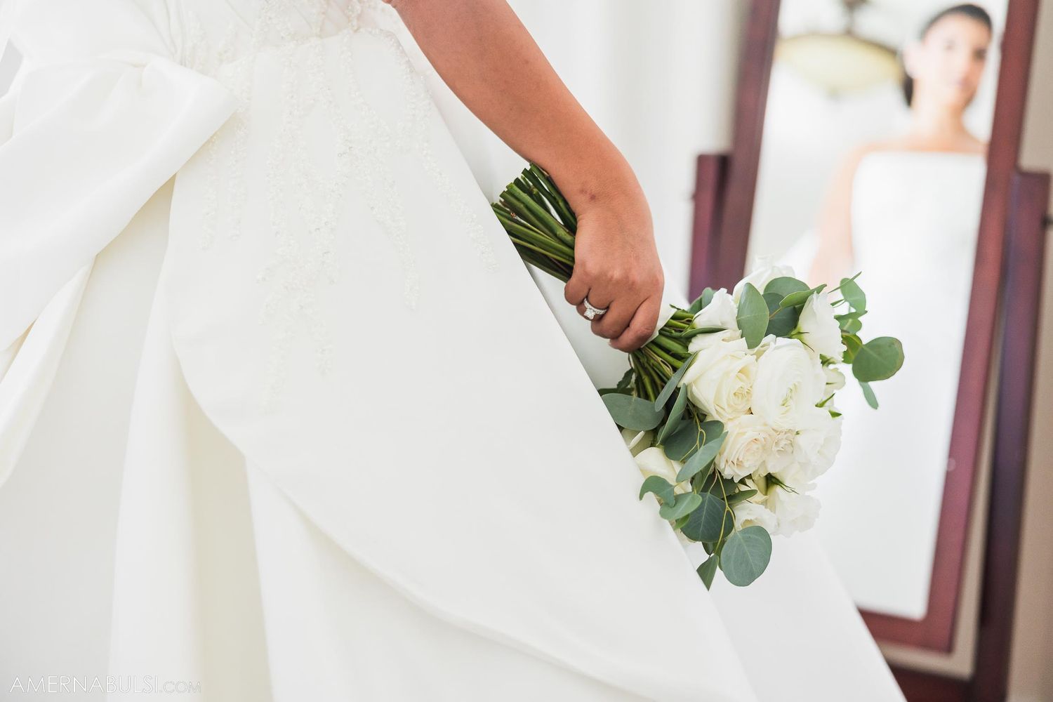 Close-up of delicate white bouquet against flowing wedding dress fabric.