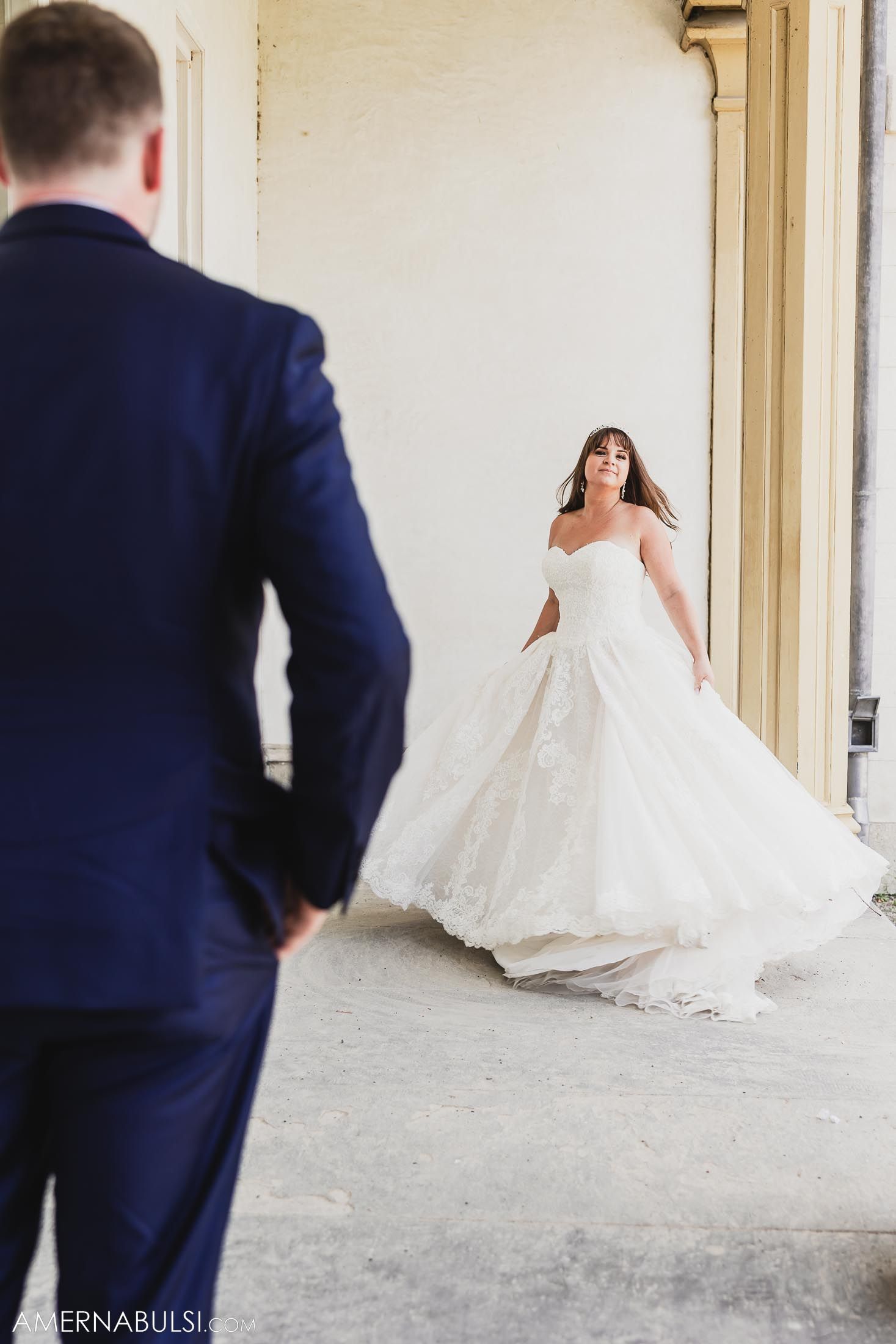 Artistic shot of couple in wedding attire framed by white architectural elements.