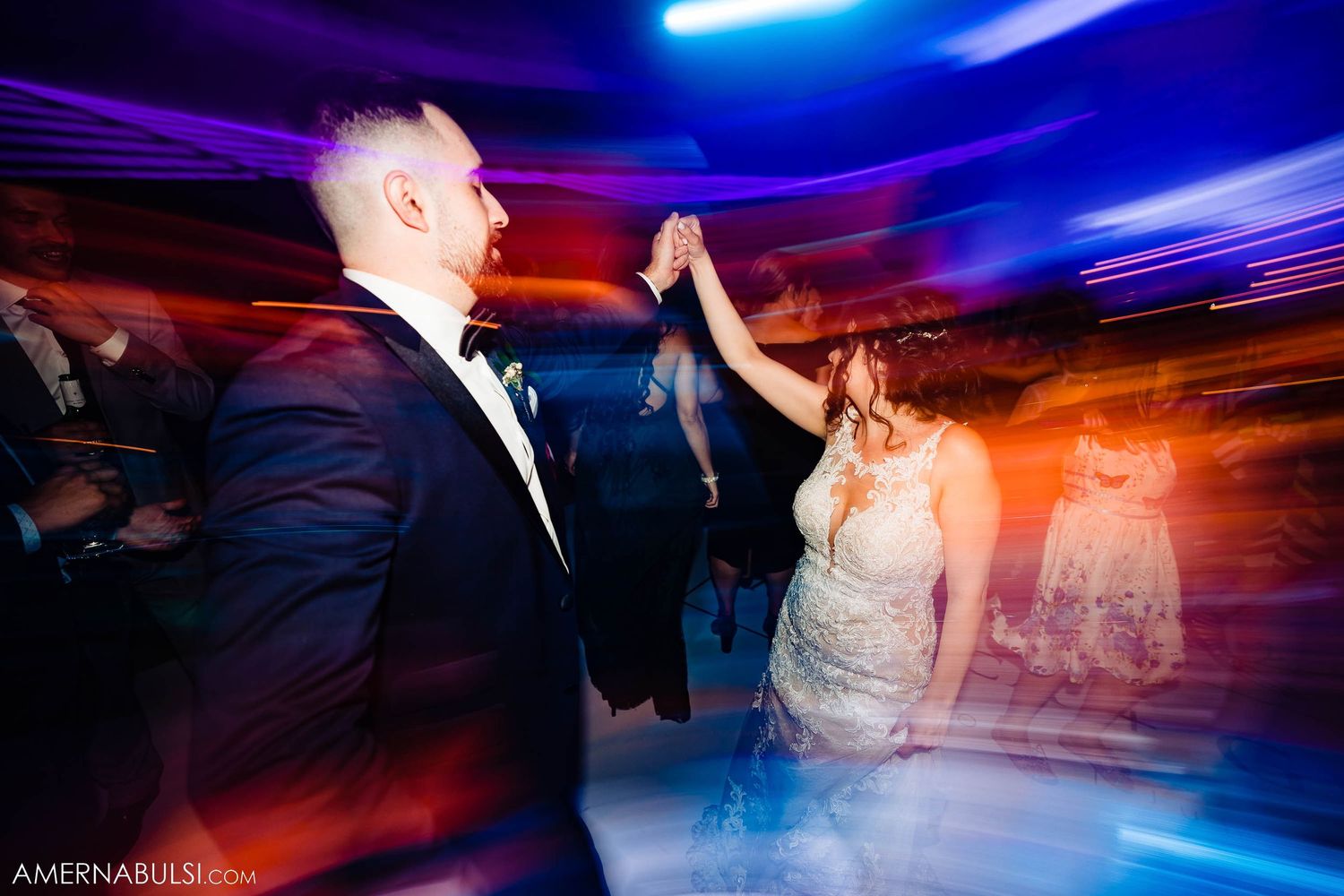 Couple dancing in motion on wedding reception dance floor with dramatic lighting effects.