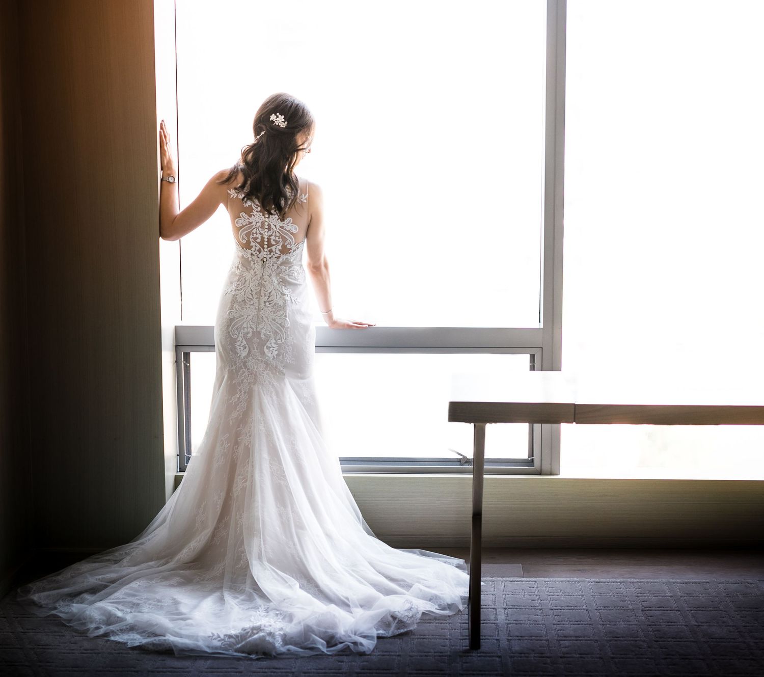 Elegant bridal gown with intricate lace details photographed in natural window light.