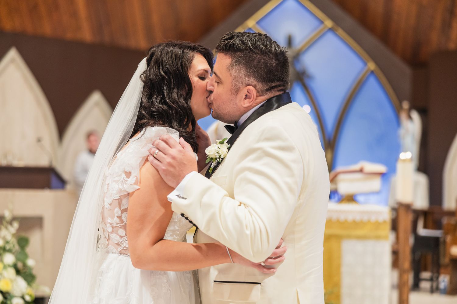 Bride and groom share their first kiss at the altar during a church wedding ceremony.