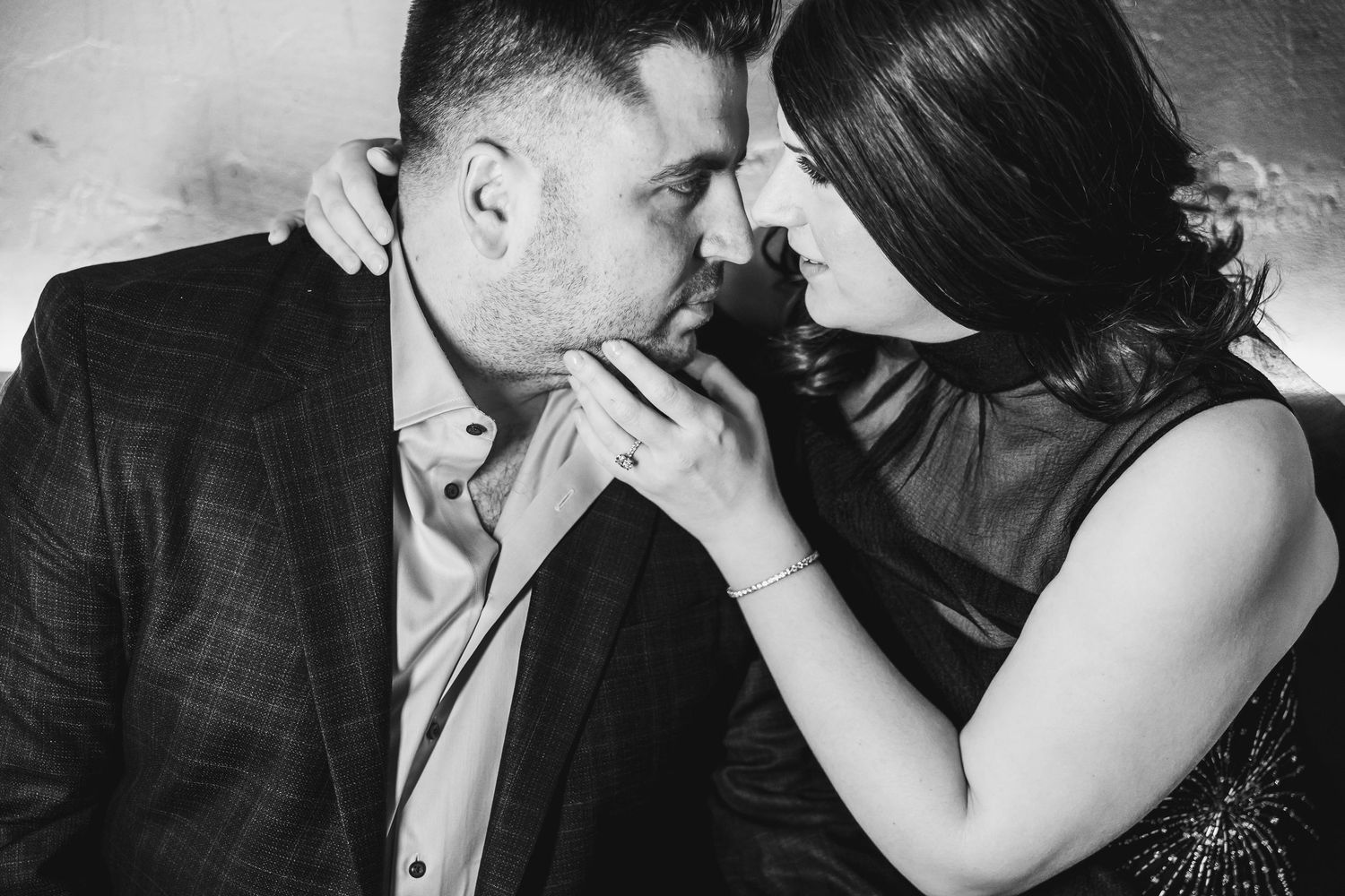Black and white romantic couple portrait, woman tenderly holding mans face as they lean close together.