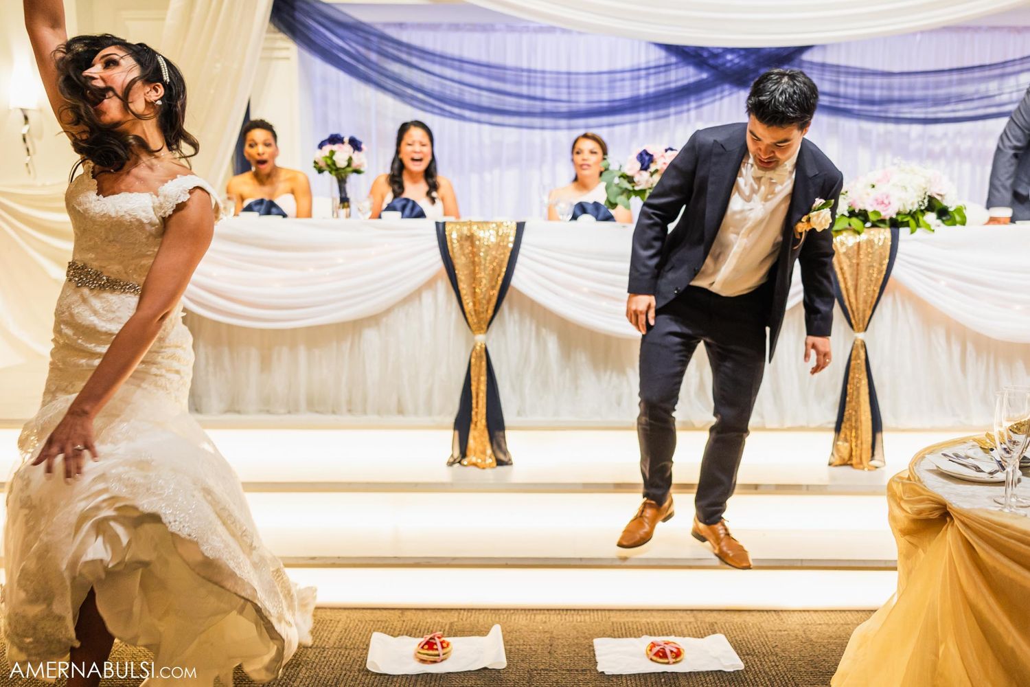 Couple shows off energetic dance moves on a raised platform at their wedding reception.