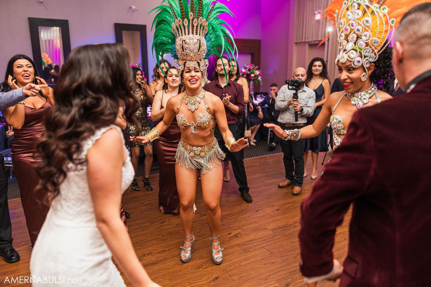 Carnival dancer in gold costume entertaining wedding guests on dance floor with purple lighting.