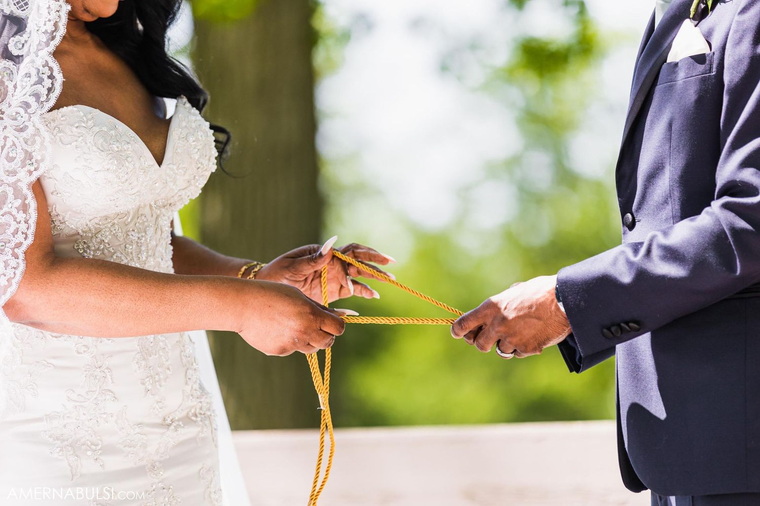 Close-up of bride and groom exchanging rings during outdoor wedding ceremony.