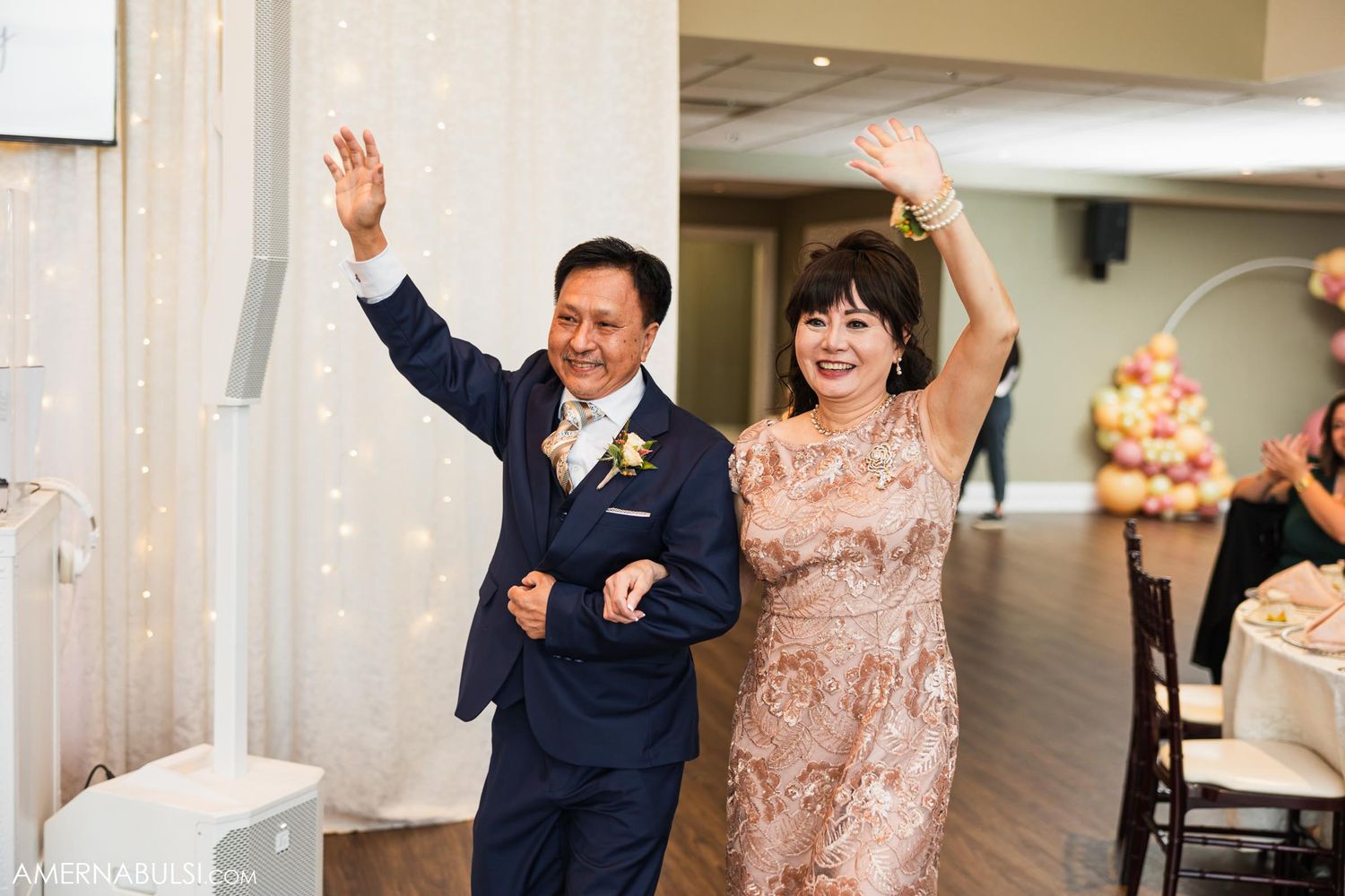 Wedding couple enthusiastically enters reception venue with raised arms and celebratory gestures.