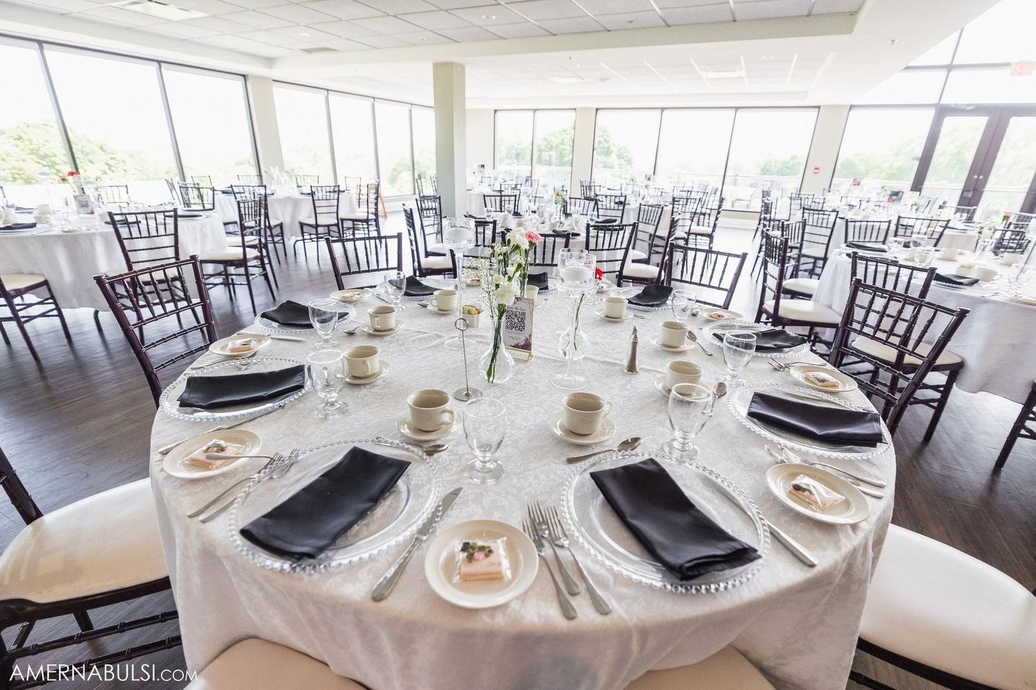 Elegant wedding reception table setting with black and white decor in bright modern venue.
