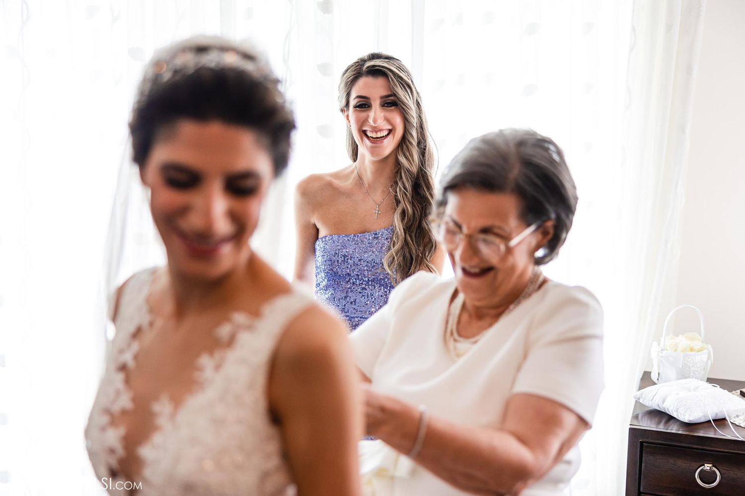 Wedding preparation scene with bridal gown being adjusted in natural window light.