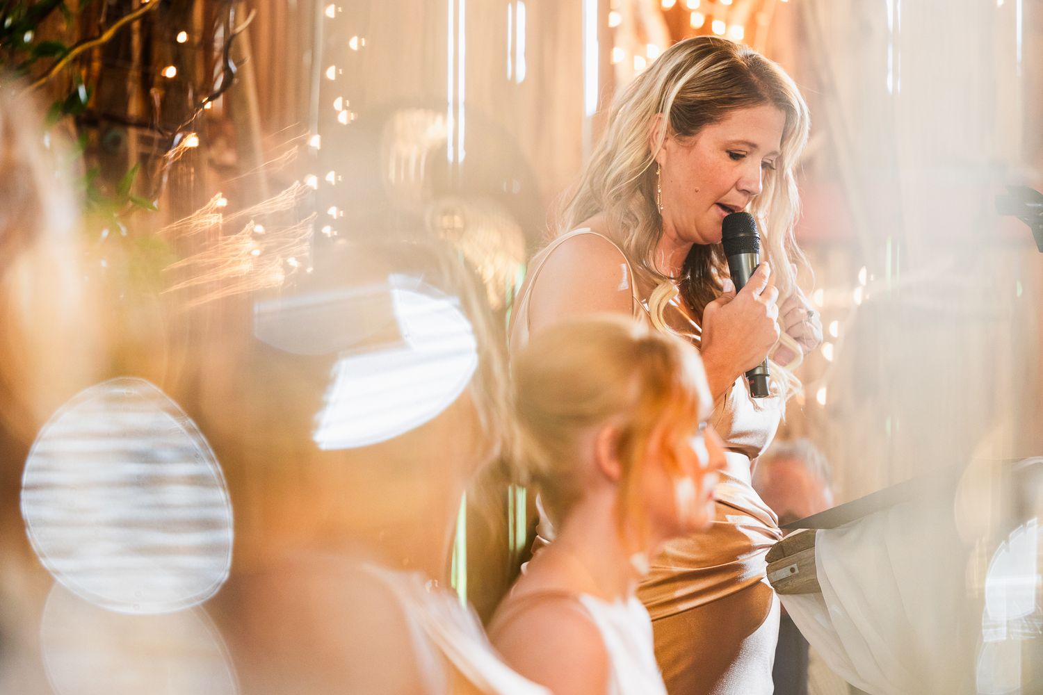 Elegant wedding party poses inside a warmly lit venue with soft focus and romantic lighting.