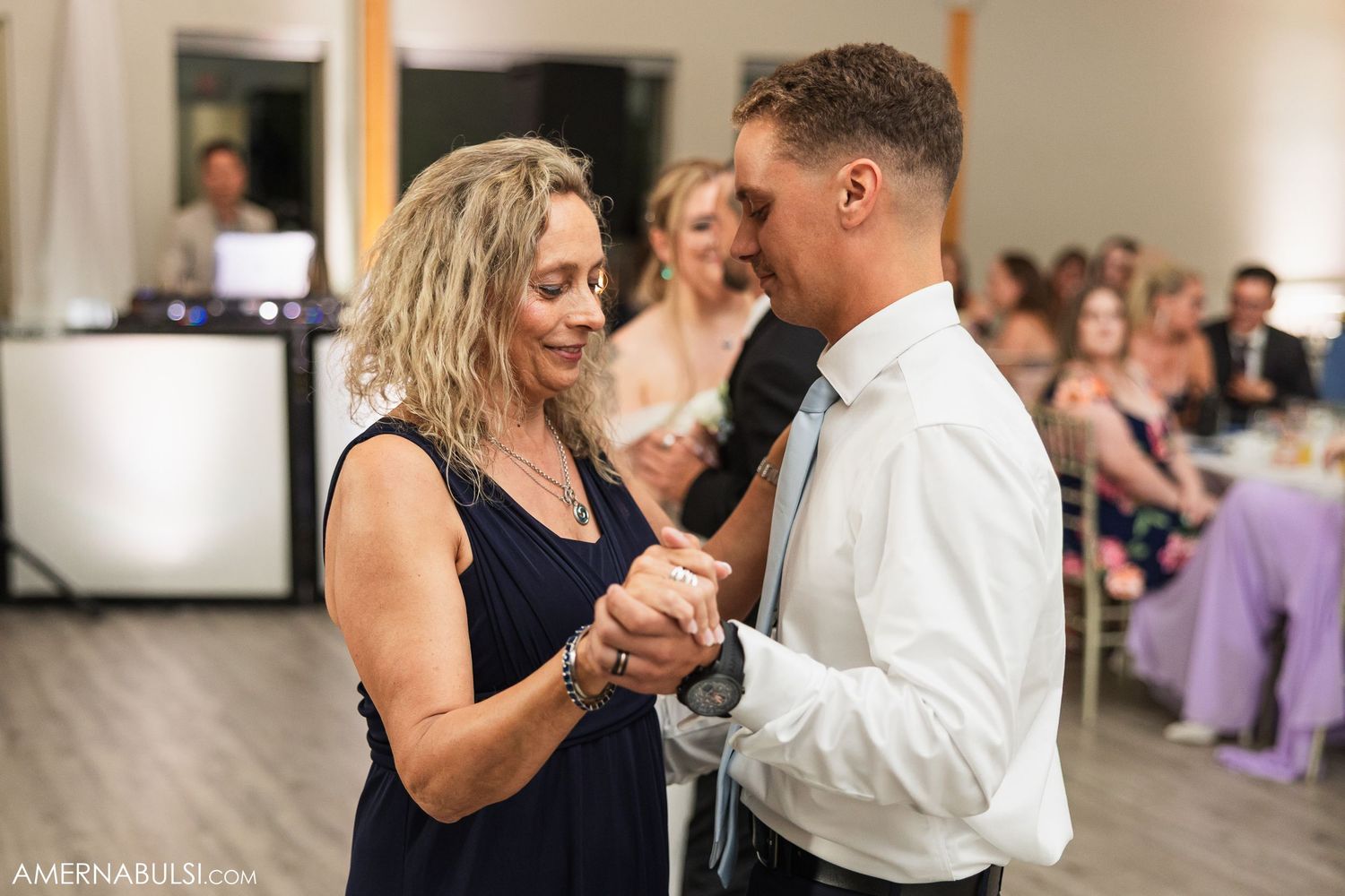 Couples slow dancing together during an indoor wedding reception with warm lighting.