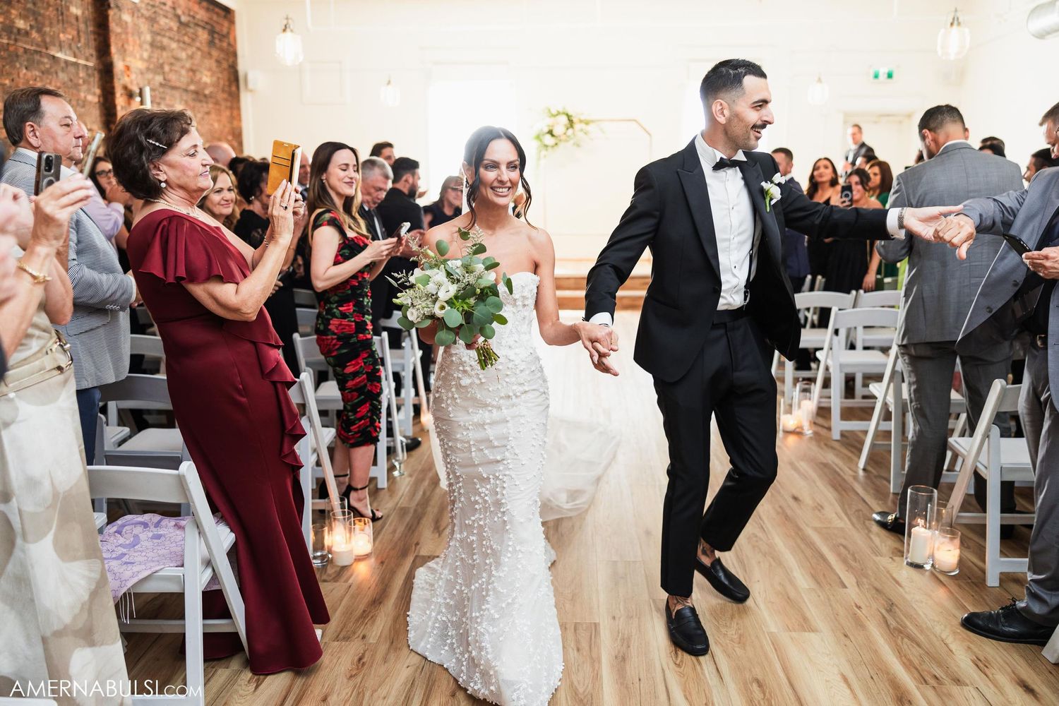 Wedding couple makes grand exit while guests cheer in ceremony venue.