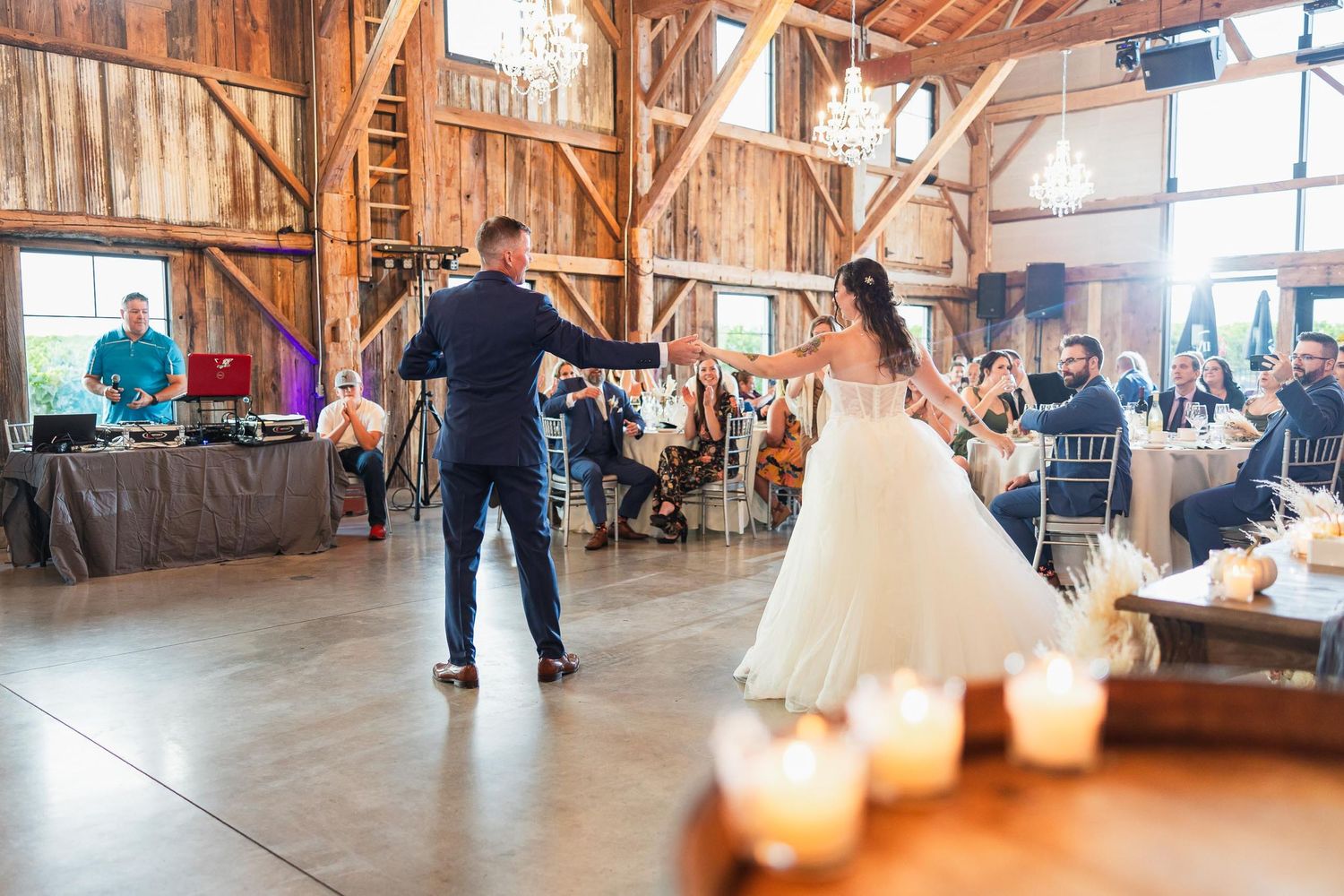 A couple dances in a rustic barn venue with candlelight and wooden beams.