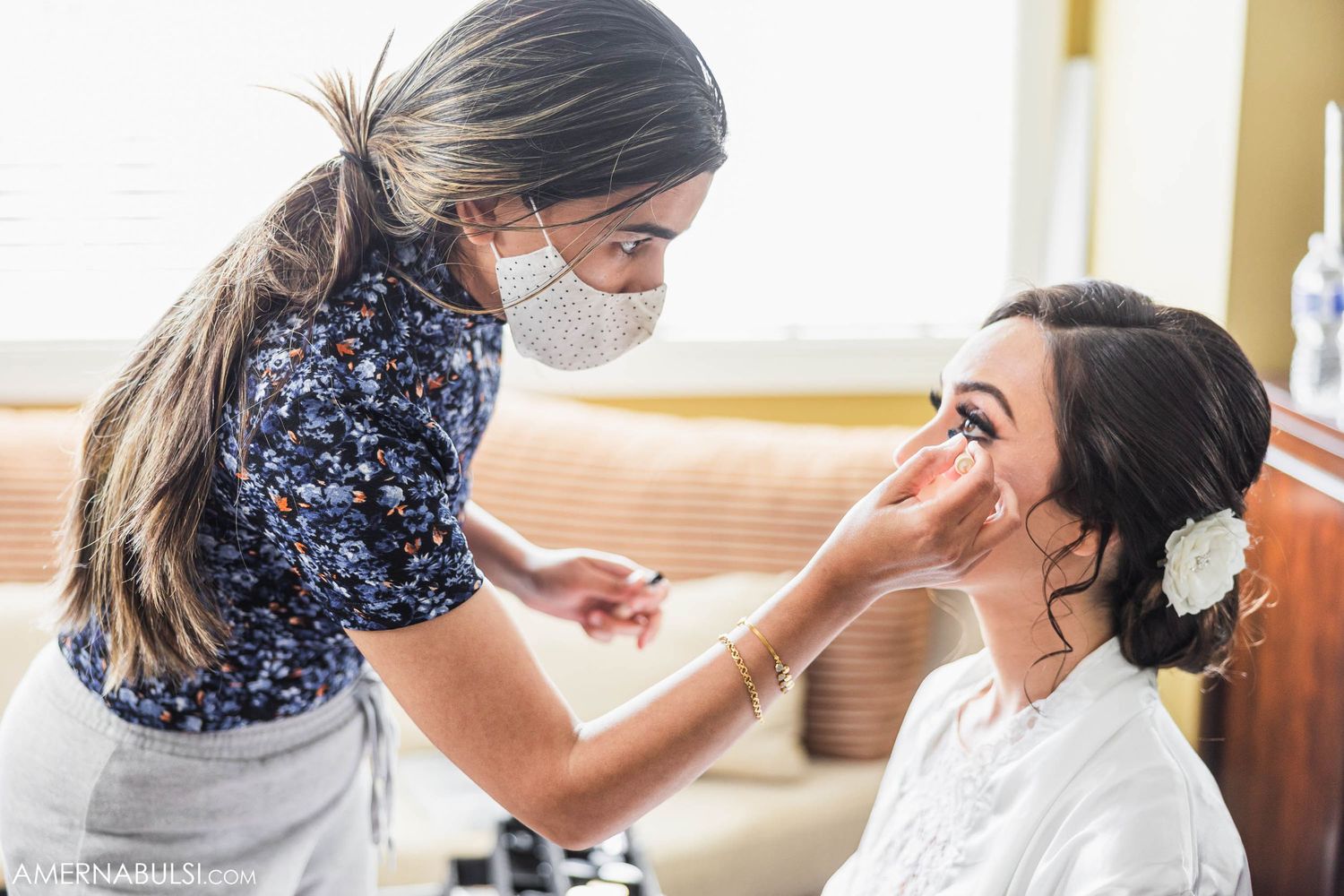 Makeup artist applying cosmetics to bride during wedding preparations.